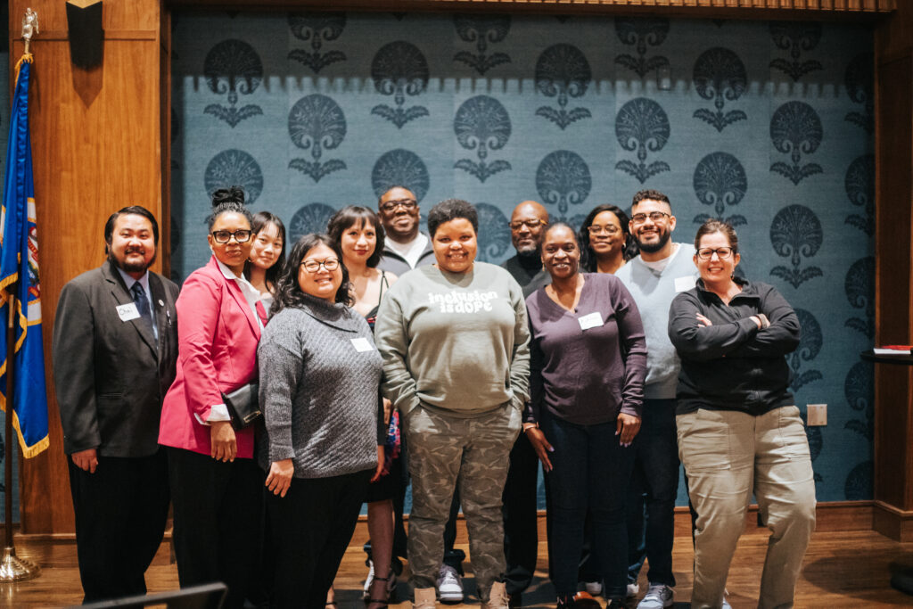 BCLI cohort 11 graduates. a multiracial mixed gender group of people standing smiling at the camera.